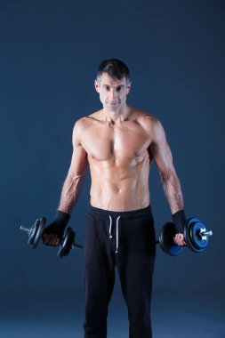 Yakışıklı kaslı adam dumbell ile çalışma dışarı. Kişisel fitness eğitmeni. Kişisel eğitim.