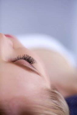 Masaj masasında uzanmış gözleri kapalı rahatlayan genç bir kadın. - Kadın. Spa salonu