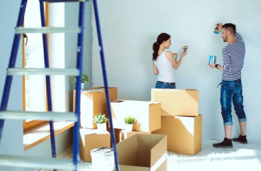 Yeni evin içini boyayan mutlu, genç bir çiftin portresi. Genç çift