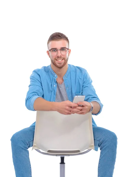 Молодой человек сидит на стуле и пользуется мобильным телефоном. Стартапер. Молодой предприниматель . — стоковое фото