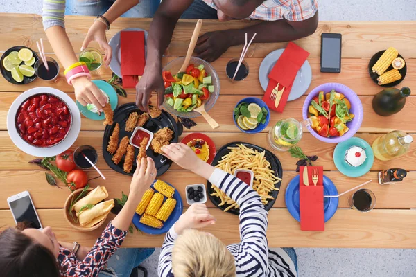 Vista dall'alto del gruppo di persone che cenano insieme seduti a un tavolo di legno. Cibo sul tavolo. La gente mangia fast food. — Foto Stock