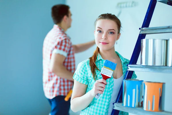 Portrait heureux sourire jeune couple peinture mur intérieur de la maison neuve. Jeune couple — Photo