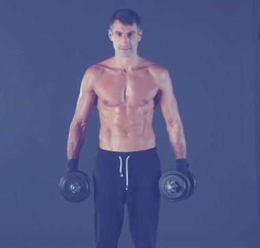 Yakışıklı kaslı adam dumbell ile çalışma dışarı. Kişisel fitness eğitmeni. Kişisel eğitim.