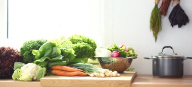 Mutfakta elinde sebzelerle gülümseyen genç bir kadın. Gülümseyen genç kadın