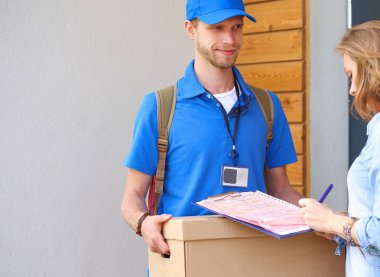 Mavi üniformalı gülümseyen kurye servis konseptine paket kutusu teslim eden teslimatçı. Mavi üniformalı gülümseyen teslimatçı.