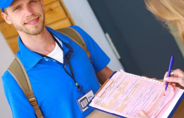 Mavi üniformalı gülümseyen kurye servis konseptine paket kutusu teslim eden teslimatçı. Mavi üniformalı gülümseyen teslimatçı.