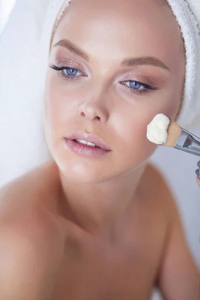 Mooie jongedame maken van make-up in de buurt van de spiegel in de badkamer — Stockfoto