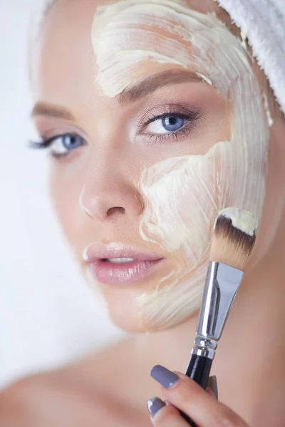 Mujer feliz con una toalla en la cabeza se pone mascarilla — Foto de Stock