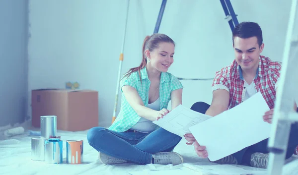 Pareja joven sentada en el suelo y calculando sobre sus ahorros. Pareja joven —  Fotos de Stock