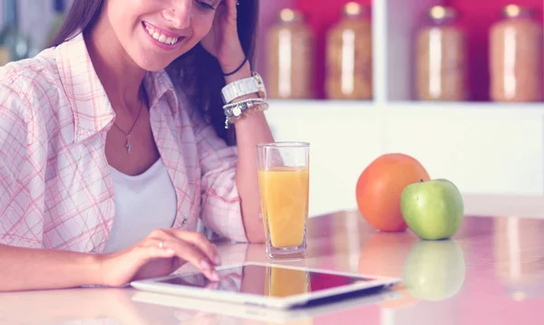 Uma jovem na cozinha, a usar o ipad. Jovem mulher — Fotografia de Stock