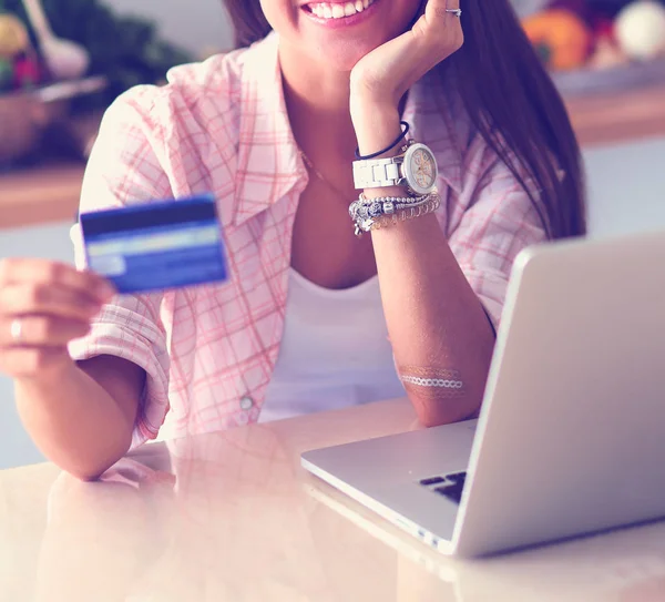 Lachende vrouw online winkelen met behulp van tablet en creditcard in de keuken. Glimlachende vrouw — Stockfoto