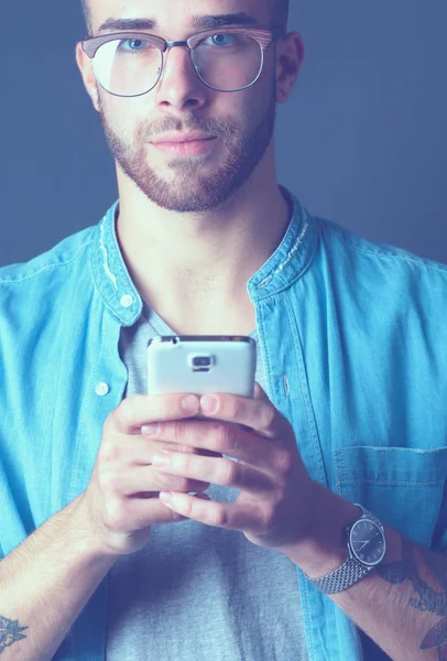 Zâmbind un tânăr care ține telefonul în timp ce trimite mesaje text — Fotografie, imagine de stoc