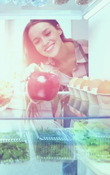 Portret kobiety stojącej w pobliżu otwartej lodówki pełnej zdrowej żywności, warzyw i owoców. — Zdjęcie stockowe