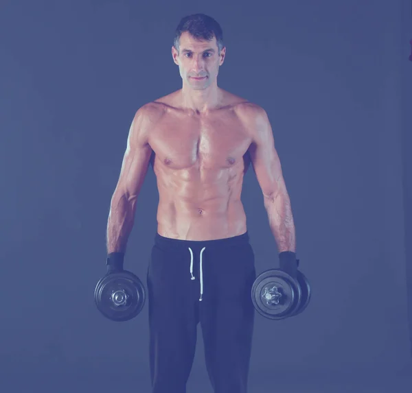 Handsome muscular man working out with dumbbells. Personal fitness instructor. Personal training. — Stock Photo, Image