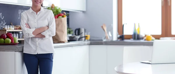 Retrato de jovem de pé com os braços cruzados contra o fundo da cozinha. Mulher na cozinha . — Fotografia de Stock