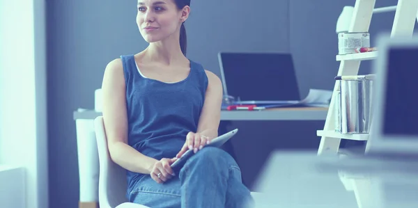 Jonge vrouw zit aan het bureau met instrumenten, plan en laptop. — Stockfoto