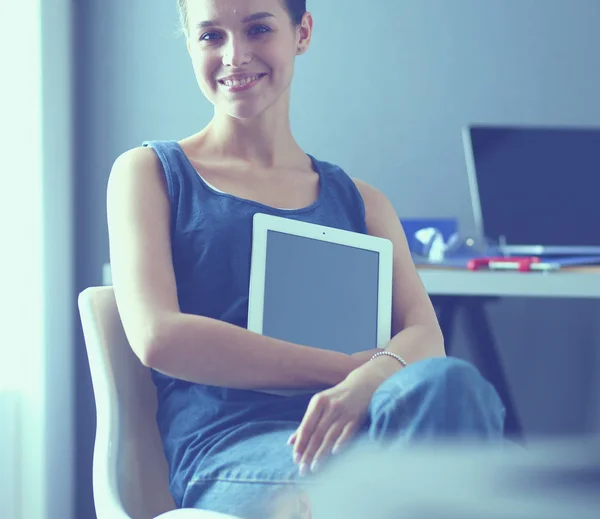 Jeune femme assise au bureau avec instruments, plan et ordinateur portable. — Photo