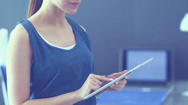 Jeune femme assise au bureau avec instruments, plan et ordinateur portable. — Photo