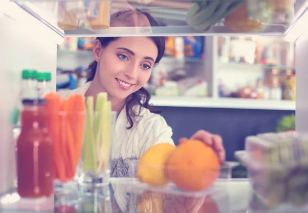 Portrait of female standing near open fridge full of healthy food, vegetables and fruits. Portrait of female — Stock Photo, Image