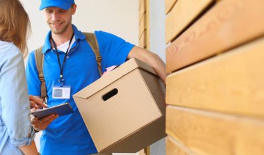 Mavi üniformalı gülümseyen kurye servis konseptine paket kutusu teslim eden teslimatçı. Mavi üniformalı gülümseyen teslimatçı.
