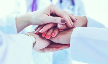 Doktorlar ve hemşireler tıbbi bir ekipte el ele tutuşuyorlar..