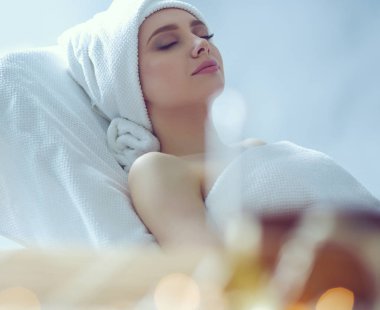 Young woman lying on a massage table,relaxing with eyes closed. Woman. Spa salon clipart