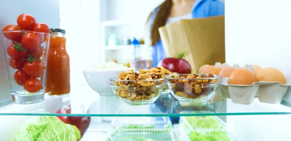 Retrato de una mujer parada cerca de una nevera abierta llena de alimentos saludables, verduras y frutas. Retrato de mujer — Foto de Stock