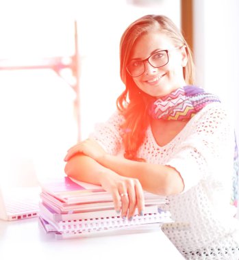 Kitapların arasında bir masada oturan genç bir kadın. Öğrenci