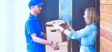 Mavi üniformalı gülümseyen kurye servis konseptine paket kutusu teslim eden teslimatçı. Mavi üniformalı gülümseyen teslimatçı.