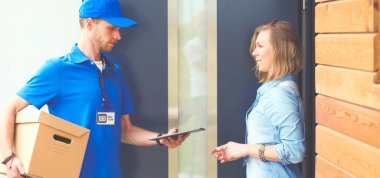 Mavi üniformalı gülümseyen kurye servis konseptine paket kutusu teslim eden teslimatçı. Mavi üniformalı gülümseyen teslimatçı.