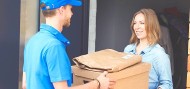 Mavi üniformalı gülümseyen kurye servis konseptine paket kutusu teslim eden teslimatçı. Mavi üniformalı gülümseyen teslimatçı.