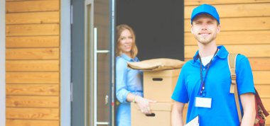 Mavi üniformalı gülümseyen kurye servis konseptine paket kutusu teslim eden teslimatçı. Mavi üniformalı gülümseyen teslimatçı.