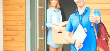 Mavi üniformalı gülümseyen kurye servis konseptine paket kutusu teslim eden teslimatçı. Mavi üniformalı gülümseyen teslimatçı.