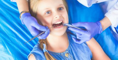 Küçük kız dişçi ofisinde oturuyor.