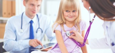 Kadın doktor ameliyatta steteskopla çocuğu muayene ediyor.