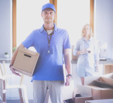 Mavi üniformalı gülümseyen kurye servis konseptine paket kutusu teslim eden teslimatçı. Mavi üniformalı gülümseyen teslimatçı.