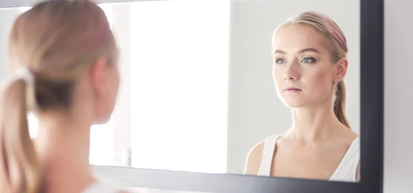 Gezicht van jonge mooie gezonde vrouw en reflectie in de spiegel — Stockfoto