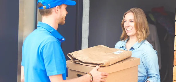 Mavi üniformalı gülümseyen kurye servis konseptine paket kutusu teslim eden teslimatçı. Mavi üniformalı gülümseyen teslimatçı. — Stok fotoğraf