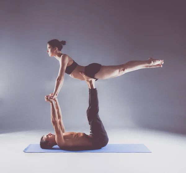 Cuplu tânăr care practică acro yoga pe mat în studio împreună. Acroyoga. Câteva yoga. Partener yoga . — Fotografie, imagine de stoc