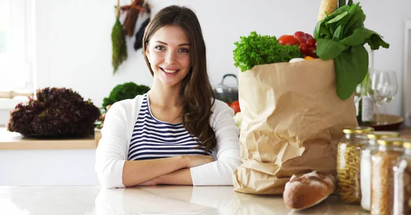 Mujer joven sosteniendo bolsa de la compra de comestibles con verduras.De pie en la cocina. Mujer joven —  Fotos de Stock