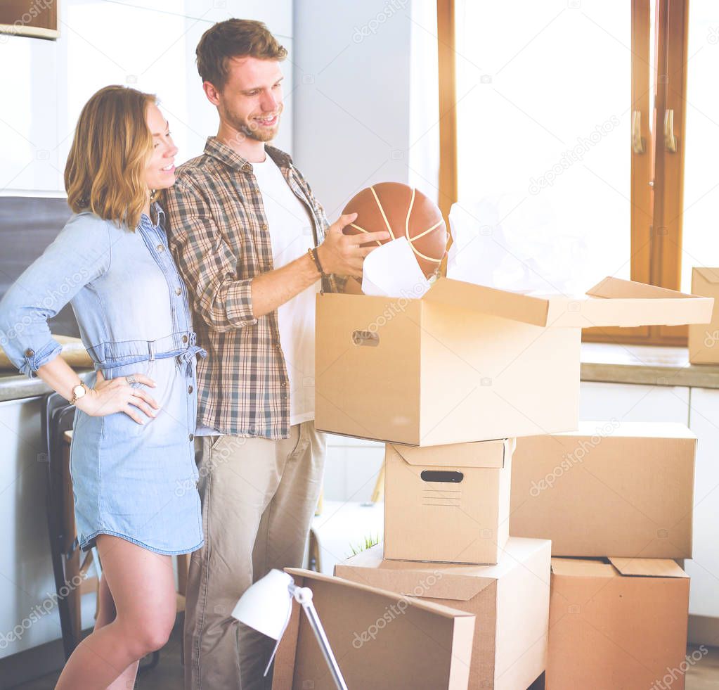 Couple unpacking cardboard boxes in their new home. Young couple.