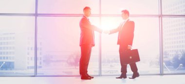 İki başarılı iş adamının el sıkışırken tam boy görüntüsü.