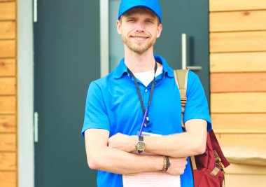 Mavi üniformalı gülümseyen kurye servis konseptine paket kutusu teslim eden teslimatçı. Mavi üniformalı gülümseyen teslimatçı.