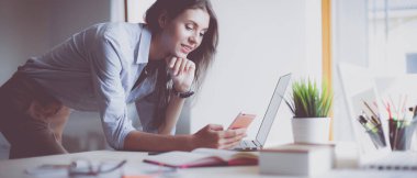 Dizüstü bilgisayar ekranına bakarak office tablosunda oturan genç kadın