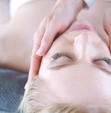 Masaj masasında uzanmış gözleri kapalı rahatlayan genç bir kadın. - Kadın. Spa salonu