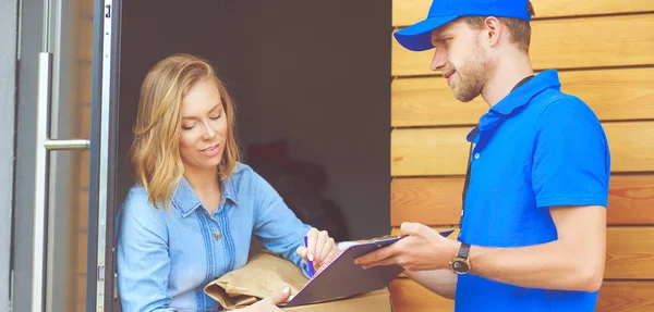 Repartidor sonriente con uniforme azul que entrega la caja de paquetes al destinatario: concepto de servicio de mensajería. Repartidor sonriente en uniforme azul — Foto de Stock