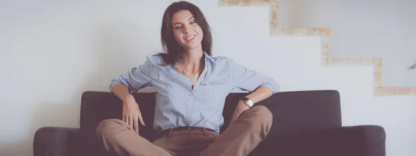 Retrato de una joven feliz sentada en un sofá — Foto de Stock