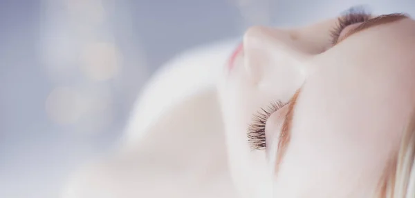 Jovem deitada em uma mesa de massagem, relaxando com os olhos fechados. Mulher. Salão de Spa — Fotografia de Stock