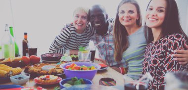 Ahşap masada otururken birlikte yemek yiyen bir grup insanın üst düzey görüntüsü. Masada yemek var. İnsanlar fast food yiyor..