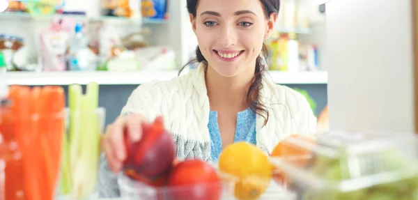 Portrait of female standing near open fridge full of healthy food, vegetables and fruits. Portrait of female — Stock Photo, Image